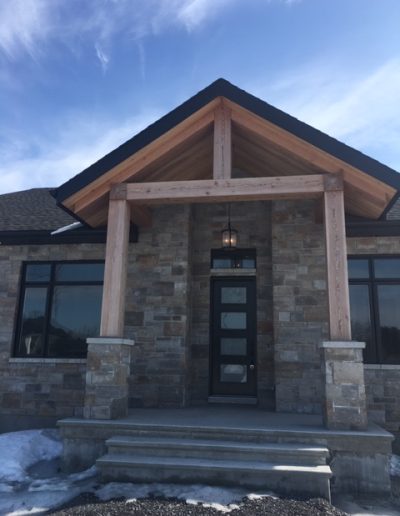 Beautiful timber frame porch with stone accents and wooden beams, showcasing custom woodwork.