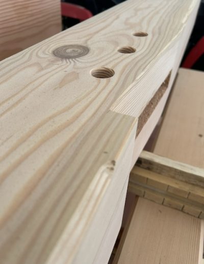 Close-up of a crafted timber beam with drilled holes at Bytown Timberworks, showcasing quality woodworking.